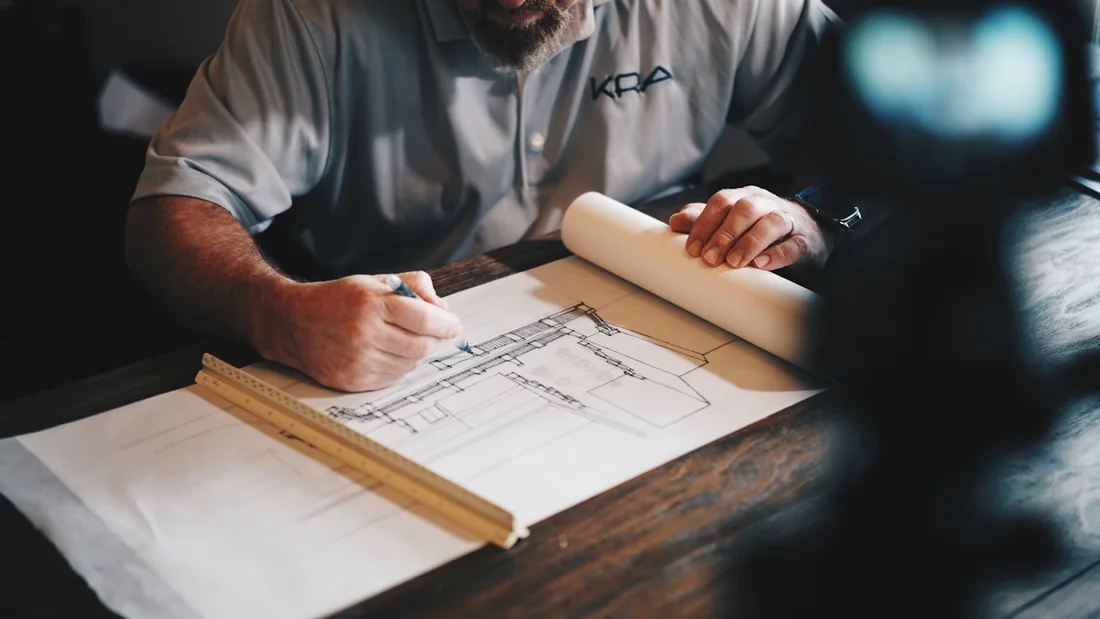 Handwerkliche Planung mit Zeichnung, Lineal und Stift auf einem Arbeitstisch